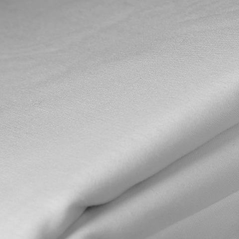 Sand colored lumbar pillow on top of a white sheet