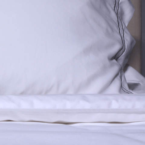 White pillow on top of a white fitted sheet